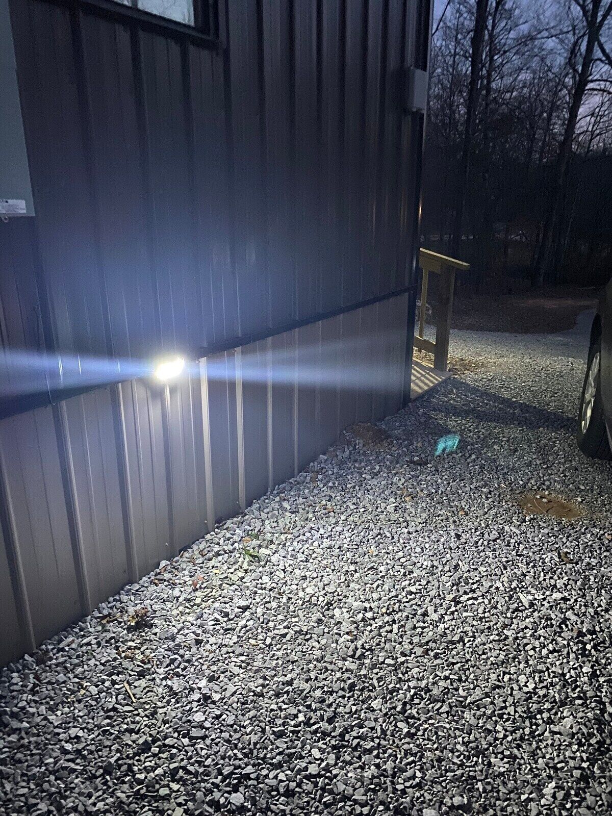 Ein Schotterweg führt zu einem Gebäude aus Metall mit einer hellen Lichtquelle.