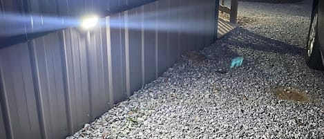 Une allée de gravier mène à un bâtiment en métal éclairé par une source de lumière vive.