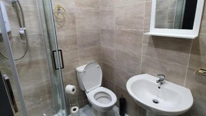 Une salle de bain avec une douche à parois de verre, des toilettes, un lavabo et un miroir au-dessus du lavabo.