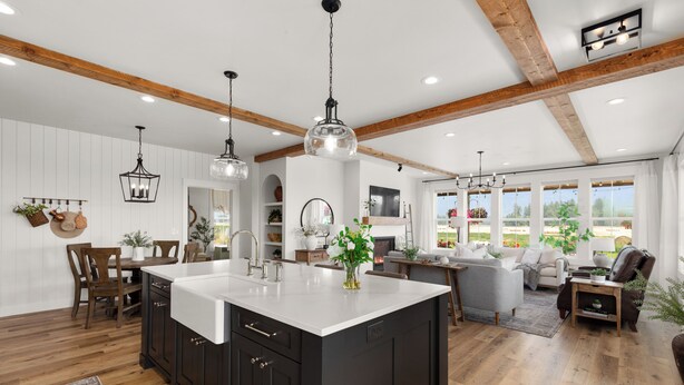 A spacious kitchen with a large island, wooden beams on the ceiling, and a dining area with a table and chairs. - Gather in Comfort: Large Property with 5 Rentals (Flathead County)