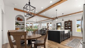 A spacious kitchen with wooden flooring, a central island, and modern pendant lighting. - Gather in Comfort: Large Property with 5 Rentals (Flathead County)