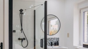 A modern bathroom with a glass-enclosed shower, a white sink with a mosaic backsplash, and a round mirror. - Cosy country B&B  (Comines-Warneton)