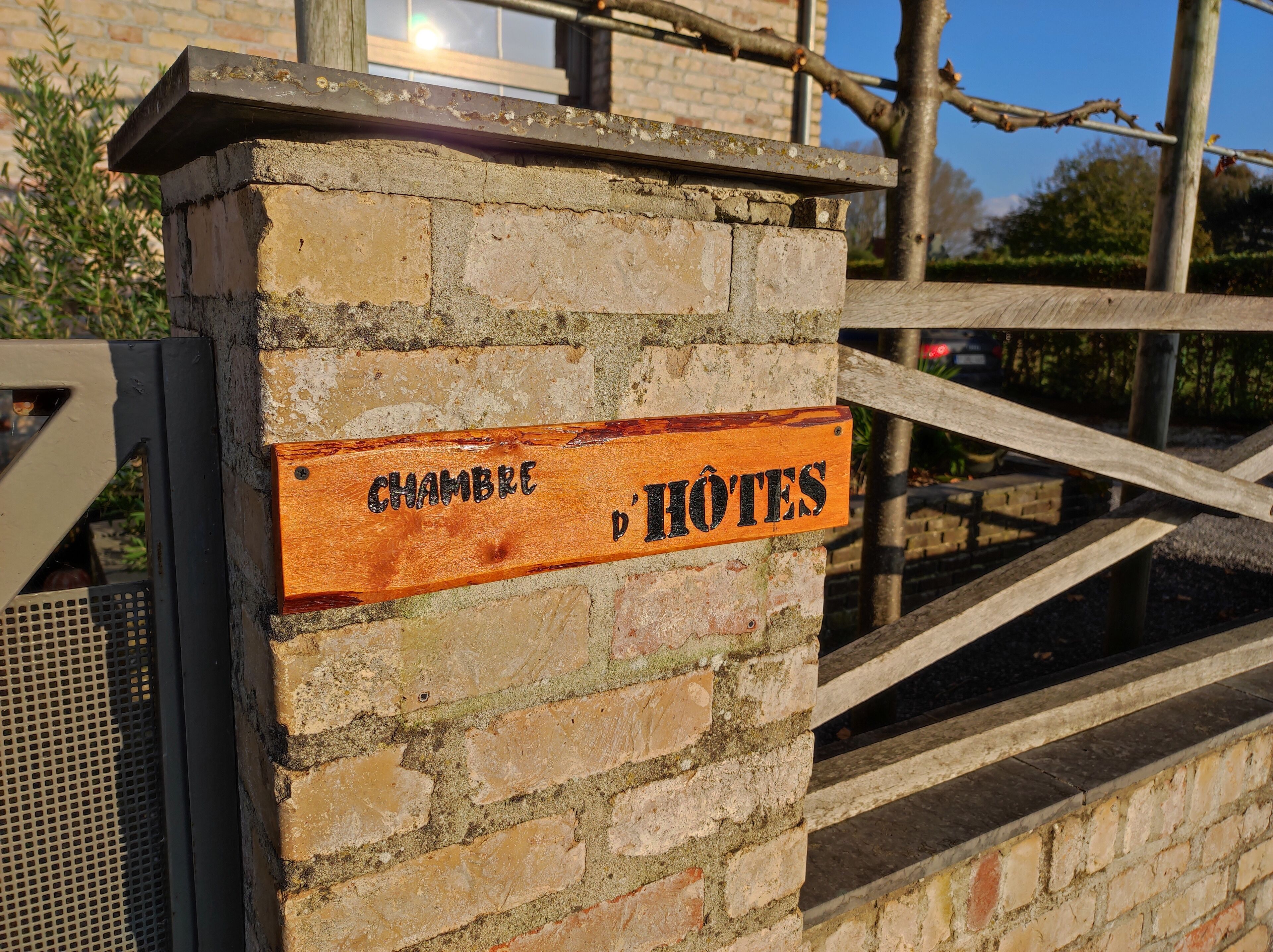 A wooden sign with "CHAMBRE D'HÔTES" indicating a hotel room.