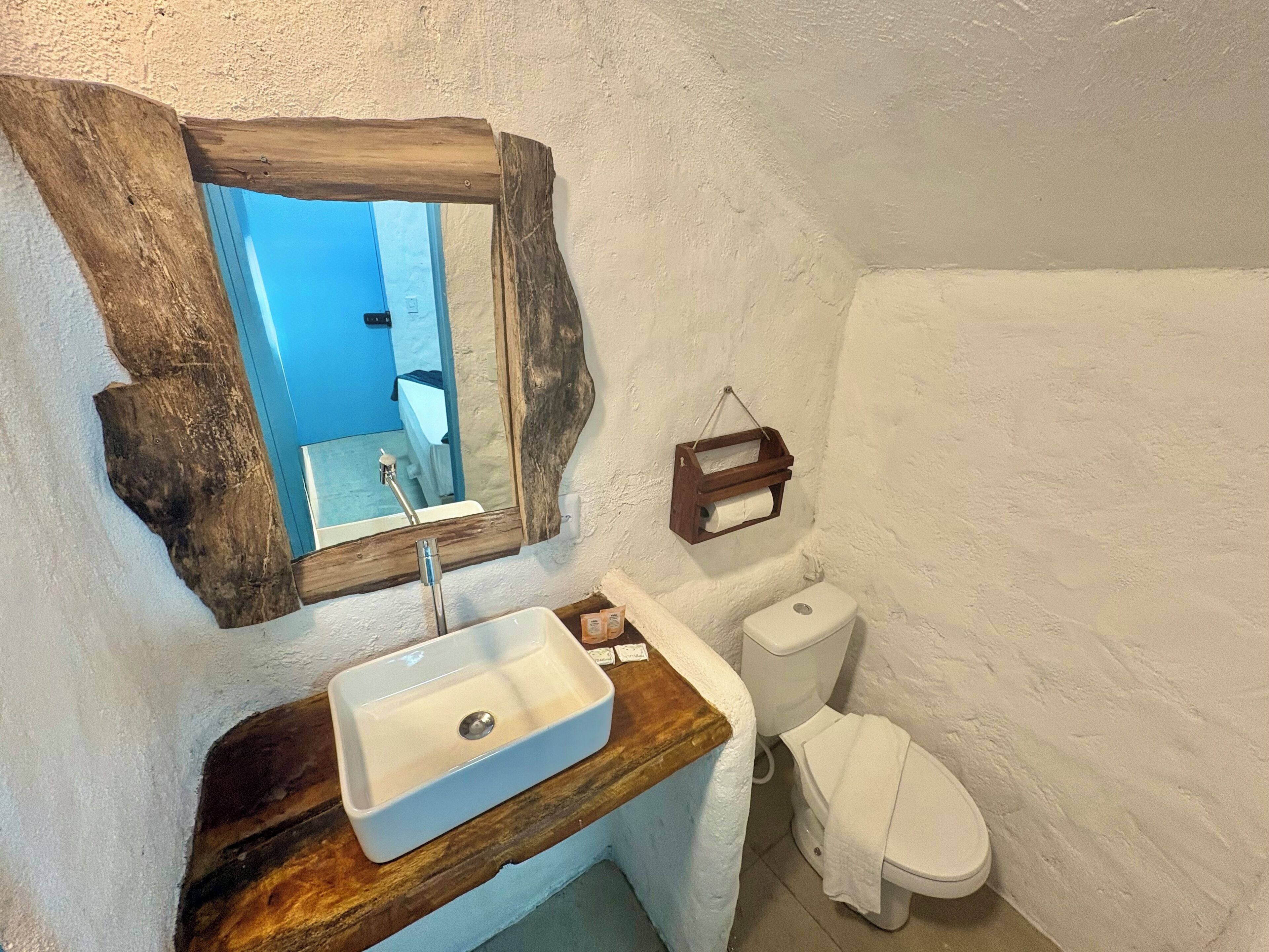 A bathroom with a wooden vanity, a white sink, a mirror, and a toilet.