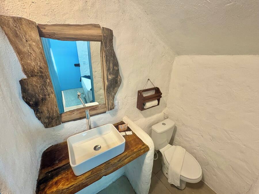 A bathroom with a wooden vanity, a white sink, a mirror, and a toilet.