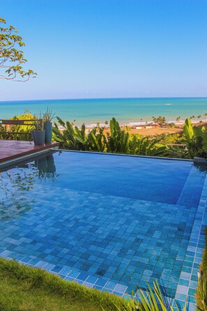 Uma piscina infinita com vista para o mar e a praia.