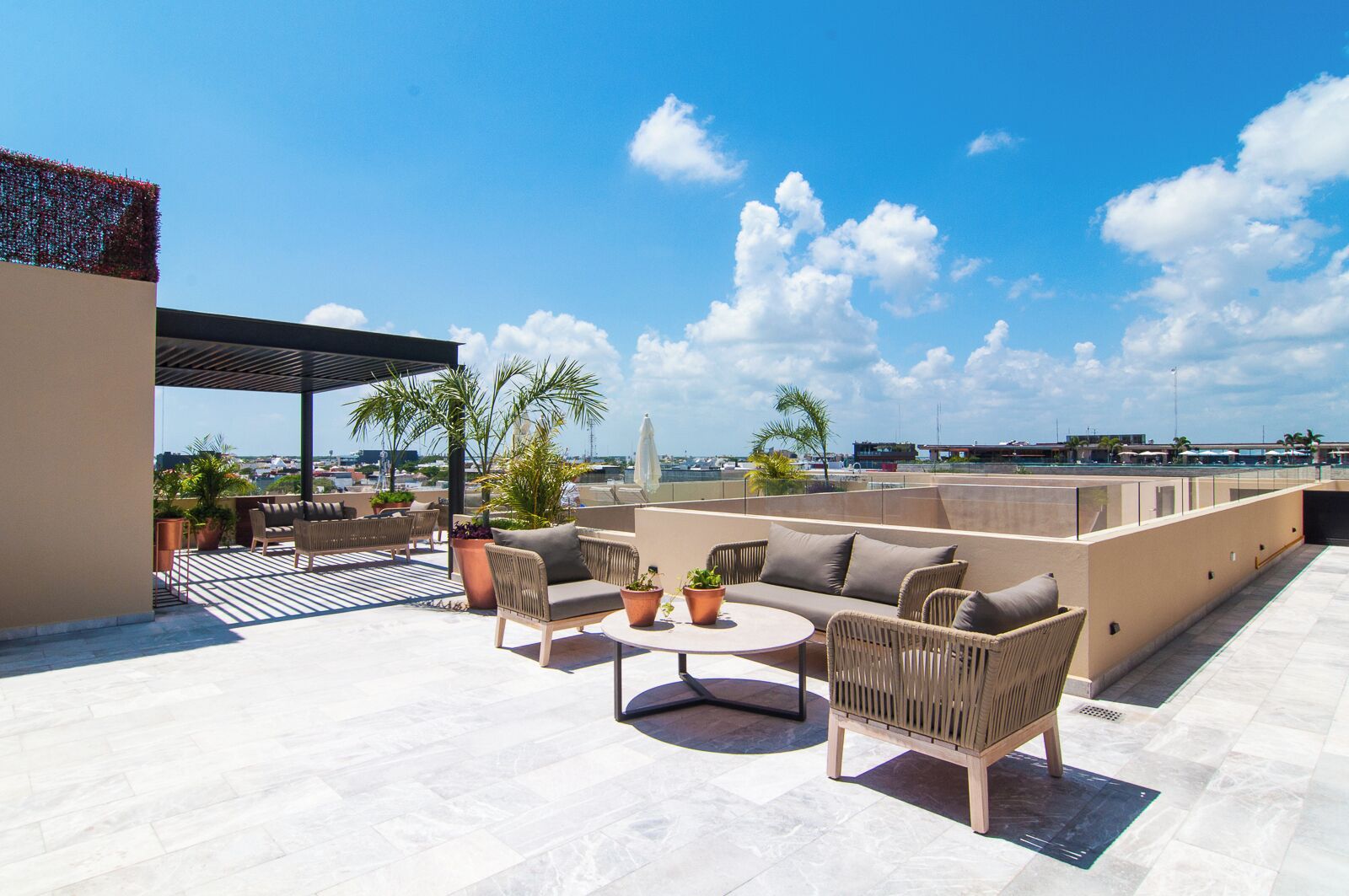 A rooftop terrace with outdoor furniture, potted plants, and a view of the cityscape.