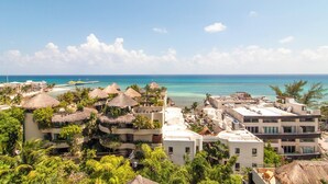 Ein Resort mit strohgedeckten Gebäuden, Palmen und Blick auf den Ozean.