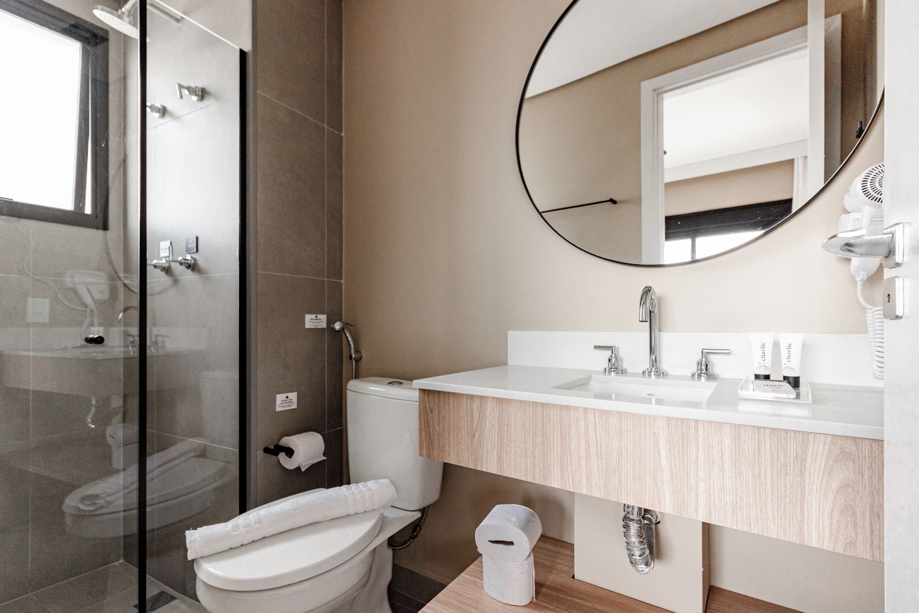 Un baño moderno con ducha de vidrio, inodoro y lavamanos con espejo.