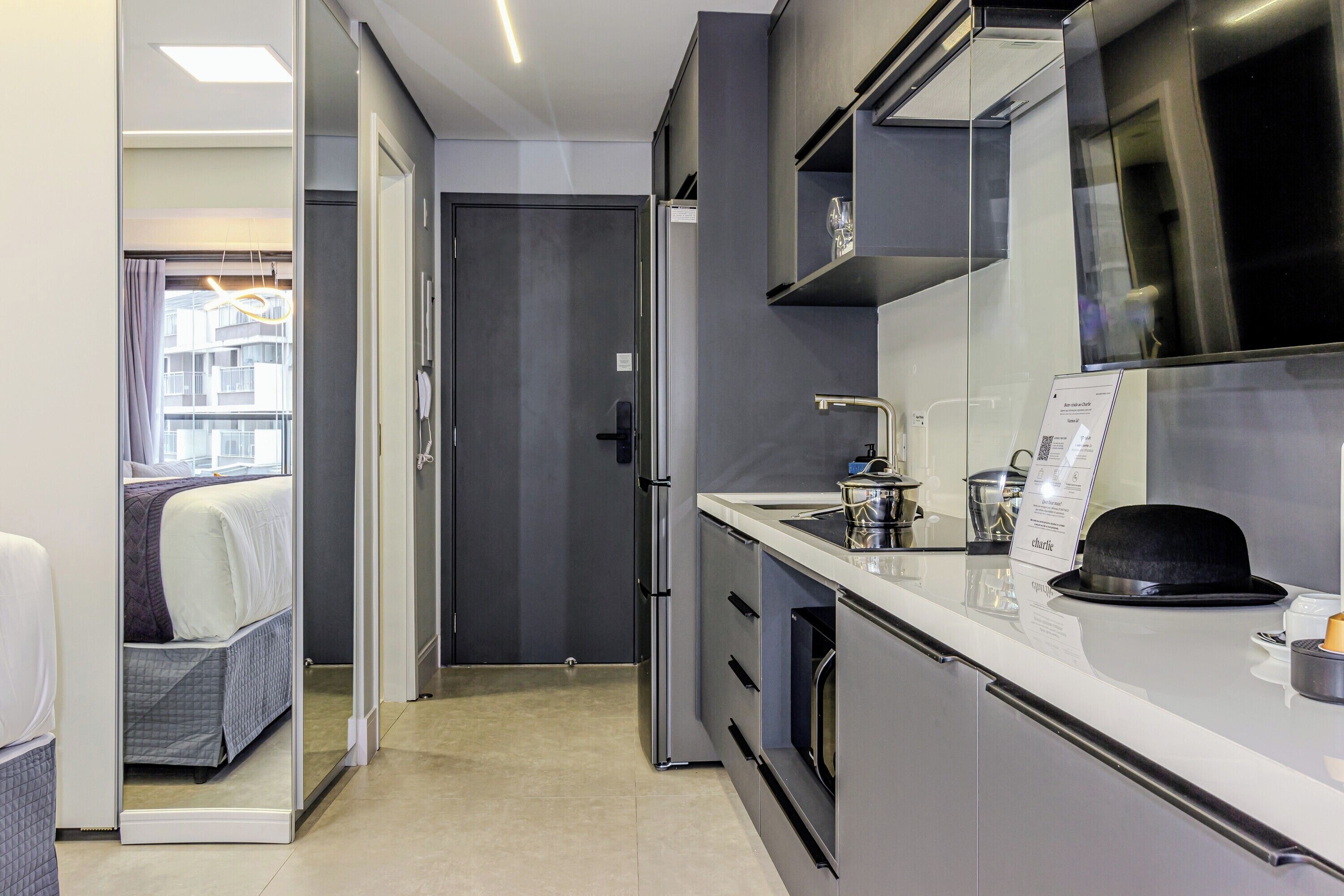 Una habitación de hotel moderna con kitchenette, una cama con vistas y una puerta que da a un balcón.