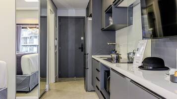 Una habitación de hotel moderna con kitchenette, una cama con vistas y una puerta que da a un balcón.