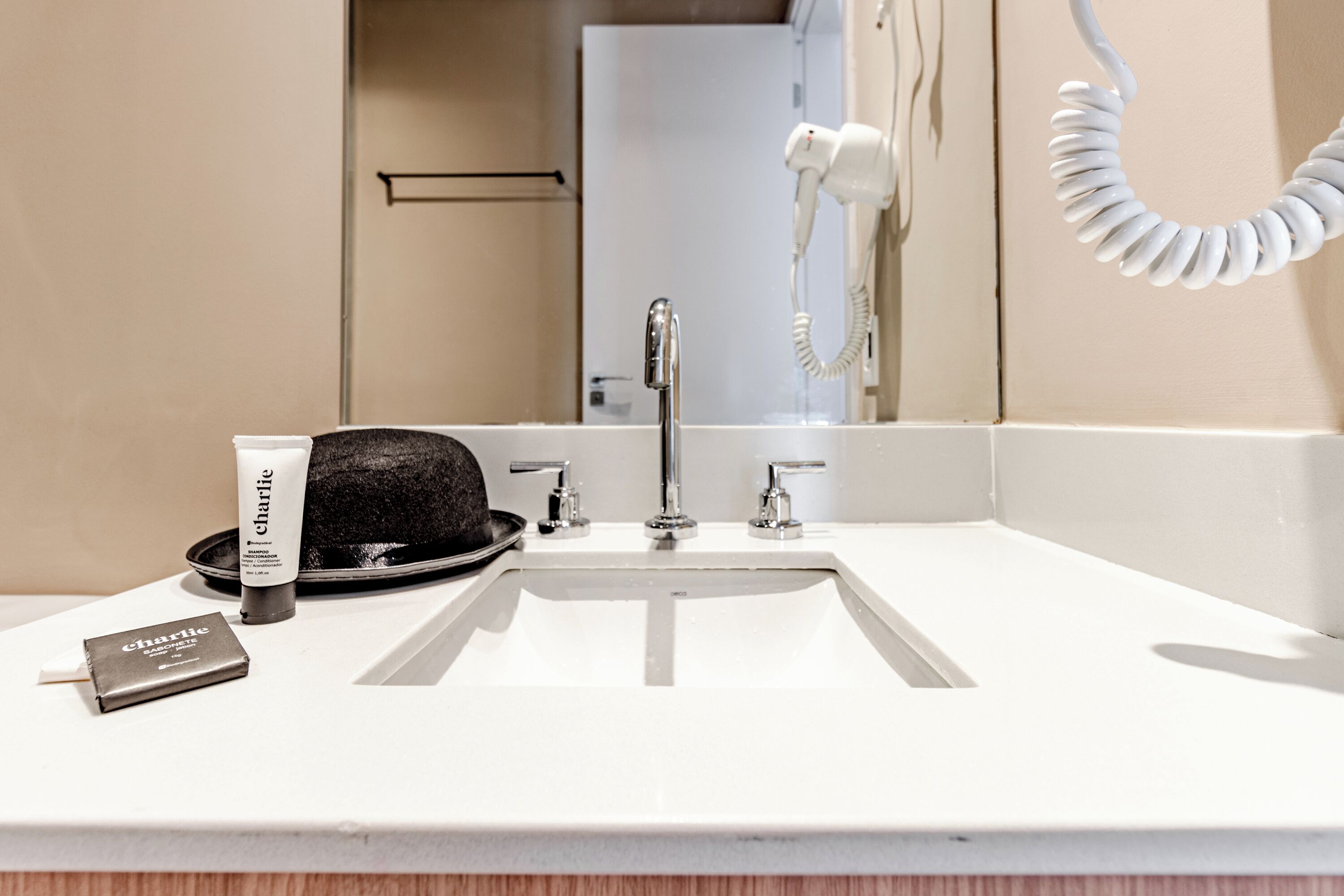 A bathroom with a white sink, a hairdryer, and a bottle of shampoo.