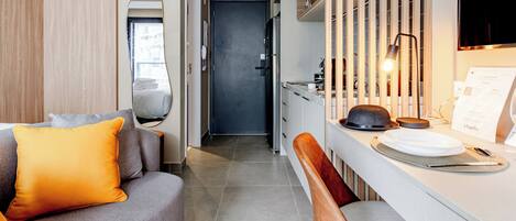 A modern kitchen with a dining area, a sofa with orange cushions, and a mirror on the wall.