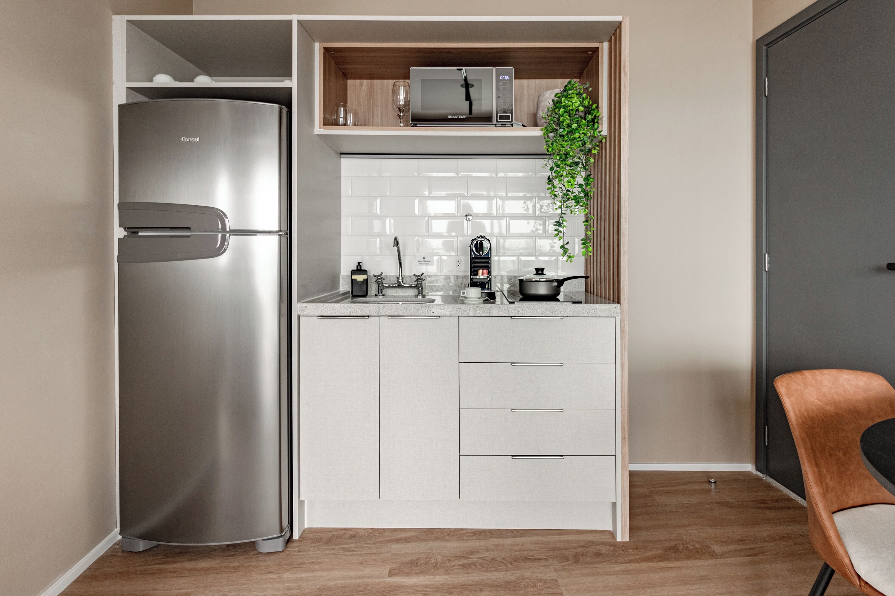 Eine kleine Küche mit einem Edelstahl-Kühlschrank, einer Mikrowelle und einem Spülbecken.