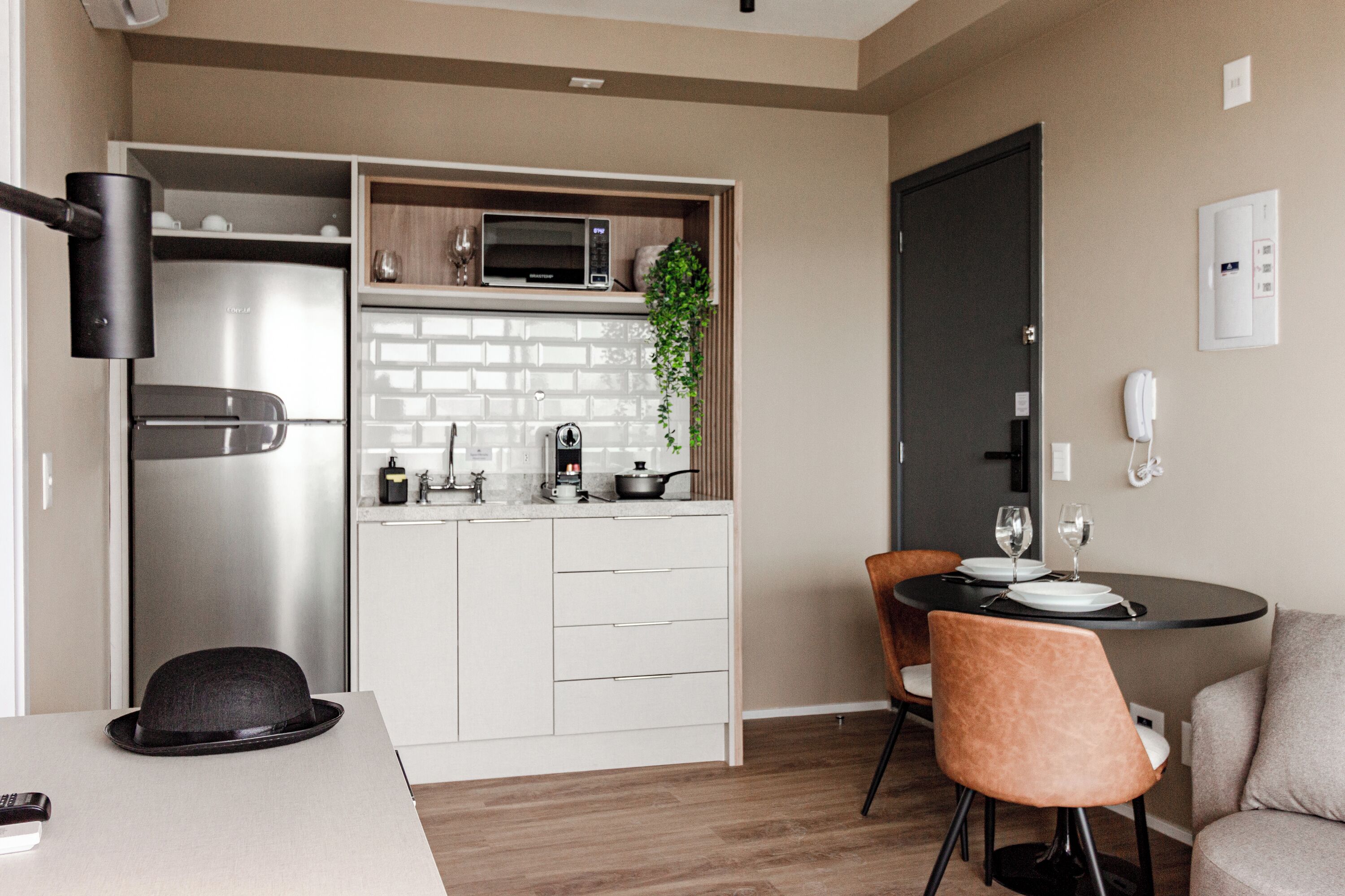 A modern kitchen with a built-in microwave, a coffee maker, and a sink. There is a dining area with a table and chairs.