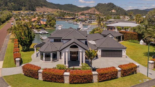 A large, modern house with a garage, a swimming pool, and a view of a lake with boats.