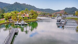 A marina with boats docked, surrounded by lush greenery and hills in the background.