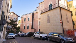 Una calle con coches aparcados, un edificio con un cartel que dice "CARABINIERI", y un cartel de prohibido el paso.