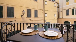 Una mesa dispuesta con platos y tazas en un balcón con vistas a edificios cercanos.