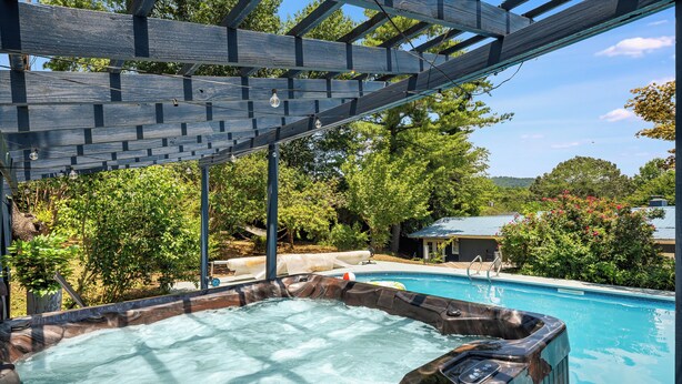 A hot tub with a wooden exterior, a pool, and a pergola structure. - HotTub, FirePit, Pets, Pool Table, Outdoor Dining (Hendersonville)