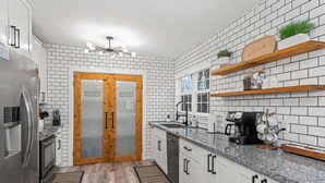 A modern kitchen with white subway tiles, a wooden door labeled 'PANTRY', stainless steel appliances, and a granite countertop. - HotTub, FirePit, Pets, Pool Table, Outdoor Dining (Hendersonville)