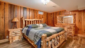 Une chambre rustique en bois, avec un lit en rondins, une table de chevet et un miroir.
