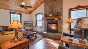 Un salon chaleureux avec une cheminée, un plafond en bois et de grandes fenêtres.