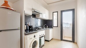 A compact kitchen with a washing machine, a stove, and a sink.