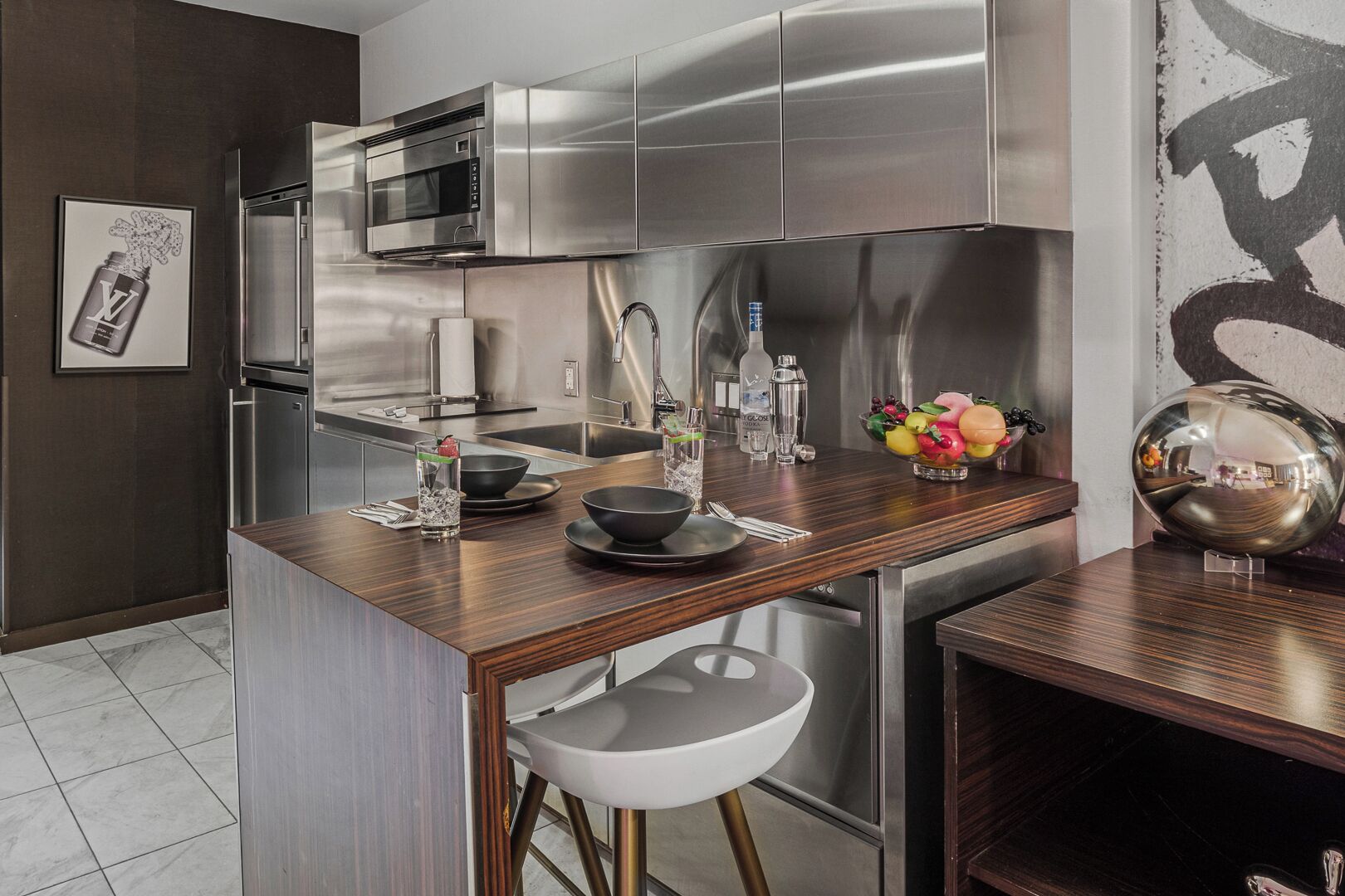 Une cuisine moderne dotée d’appareils électroménagers en acier inoxydable, d’un îlot central en bois et d’un tabouret de bar.