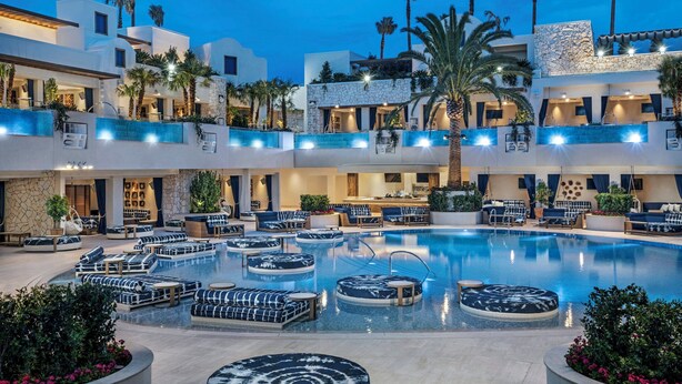 Un hotel de varios niveles con una piscina central rodeada de zonas de descanso y asientos.