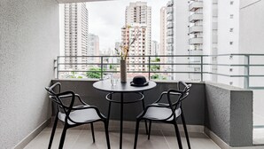 A balcony with a round table and four chairs, overlooking a cityscape with tall buildings. - Charlie Mode Perdizes (São Paulo)