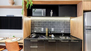 A modern kitchen with a built-in microwave, a sink, and a refrigerator. - Charlie Mode Perdizes (São Paulo)