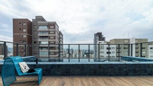 A rooftop terrace with a pool, a blue chair, and a view of surrounding buildings. - Charlie Mode Perdizes (São Paulo)