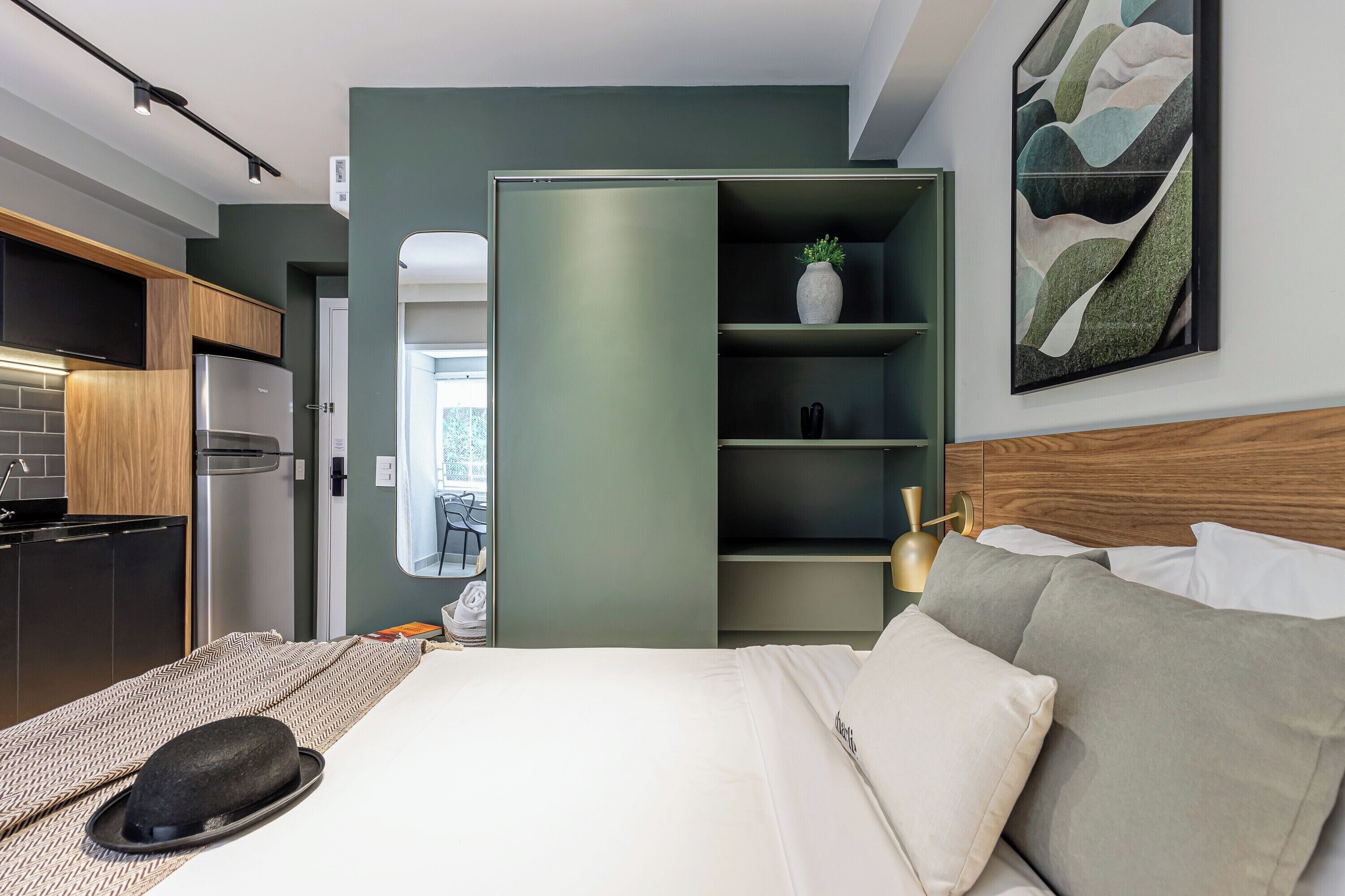 Ein modernes Hotelzimmer mit Bett, Schrank, Küchenzeile und Blick ins Freie.
