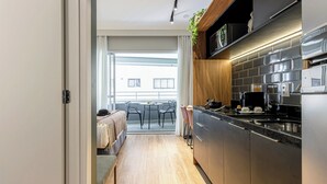 A modern kitchen with stainless steel appliances, a wooden countertop, and a view to an outdoor balcony. - Charlie Mode Perdizes (São Paulo)