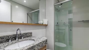 Un bany modern amb un lavabo amb taulell de granat, un mirall damunt i una dutxa amb envàs de vidre.
