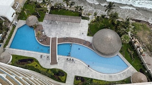 An aerial view of a resort with a large pool, palm trees, and a beach. - Luxury  2 Bedrooms Apartment at an exclusive tower by the beach in Zona Dorada 
 (Mazatlán)