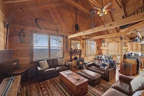 A log cabin interior with a fireplace, leather sofas, a dining area, and a kitchen. - Owl’s Hollow - Stunning Brow View (Mentone)