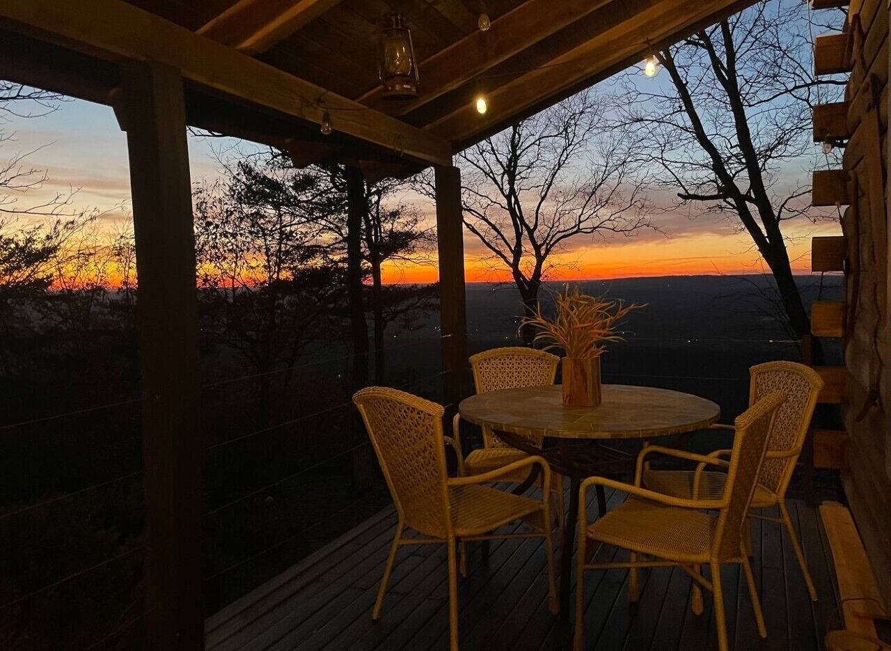 Un espace extérieur aménagé avec des meubles de jardin en osier, comprenant des chaises et une table ronde, offrant une vue imprenable sur le coucher du soleil.