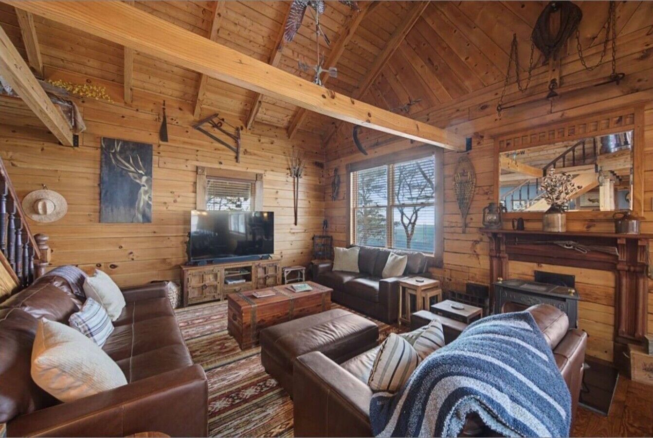 L’intérieur d’un chalet rustique, avec des murs en bois, une cheminée, un téléviseur et un coin salon confortable.