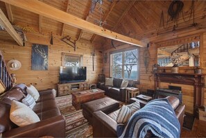 A rustic cabin interior with wooden walls, a fireplace, a television, and a cozy seating area. - Owl’s Hollow - Stunning Brow View (Mentone)