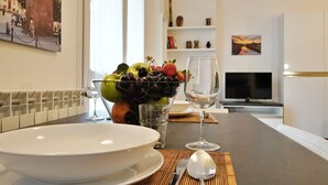 A dining table with a bowl, a glass of wine, and a fruit bowl. -  Rentopolis Apartments - Palazzo Candiani (Milan)