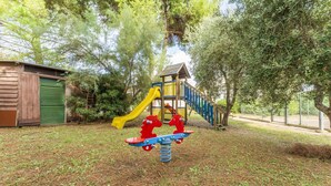 Une aire de jeux avec un toboggan, une structure d’escalade et une balançoire.