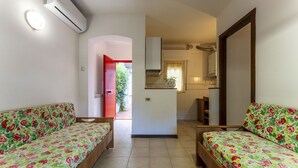 Une chambre avec deux lits, une kitchenette et une salle de bain.