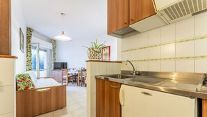 Une cuisine de taille réduite, dotée de meubles en bois, d’un évier en acier inoxydable et d’un réfrigérateur compact.