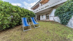 Une maison dotée d’un patio couvert, de deux fauteuils bleus et d’une petite table.