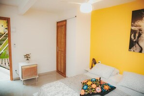 A bedroom with a bed, a bedside table, a small cabinet, a wooden door, and a yellow wall. - Double Room with Sea View and Private Bathroom (Leme Rio de Janeiro)