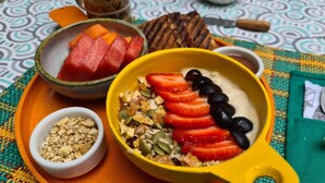 A breakfast setting with a bowl of yogurt topped with strawberries and blackberries, a bowl of granola, and a bowl of watermelon. - Double Room with Shared Bathroom (Leme Rio de Janeiro)