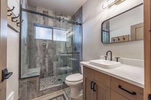 Een moderne badkamer met een douchecabine van glas, een wit toilet en een wastafel met een wastafel en spiegel.