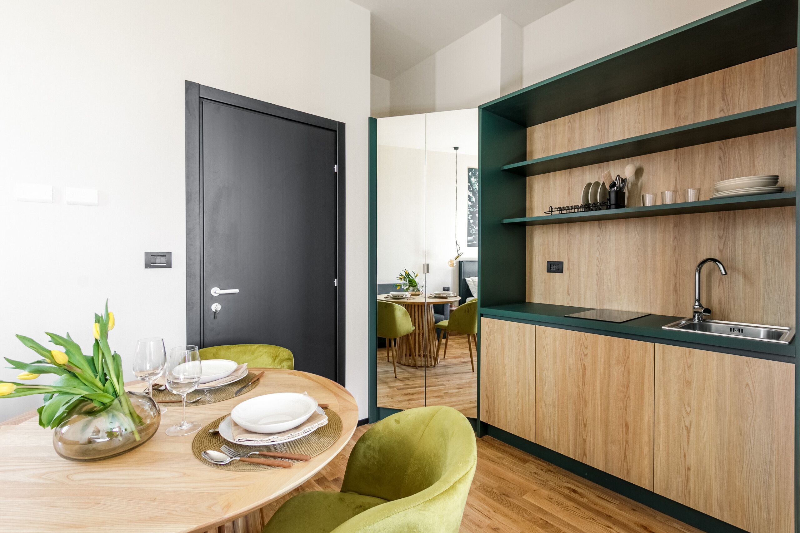 Une cuisine moderne avec des meubles en bois, un évier et un coin repas comprenant une table ronde et des chaises.
